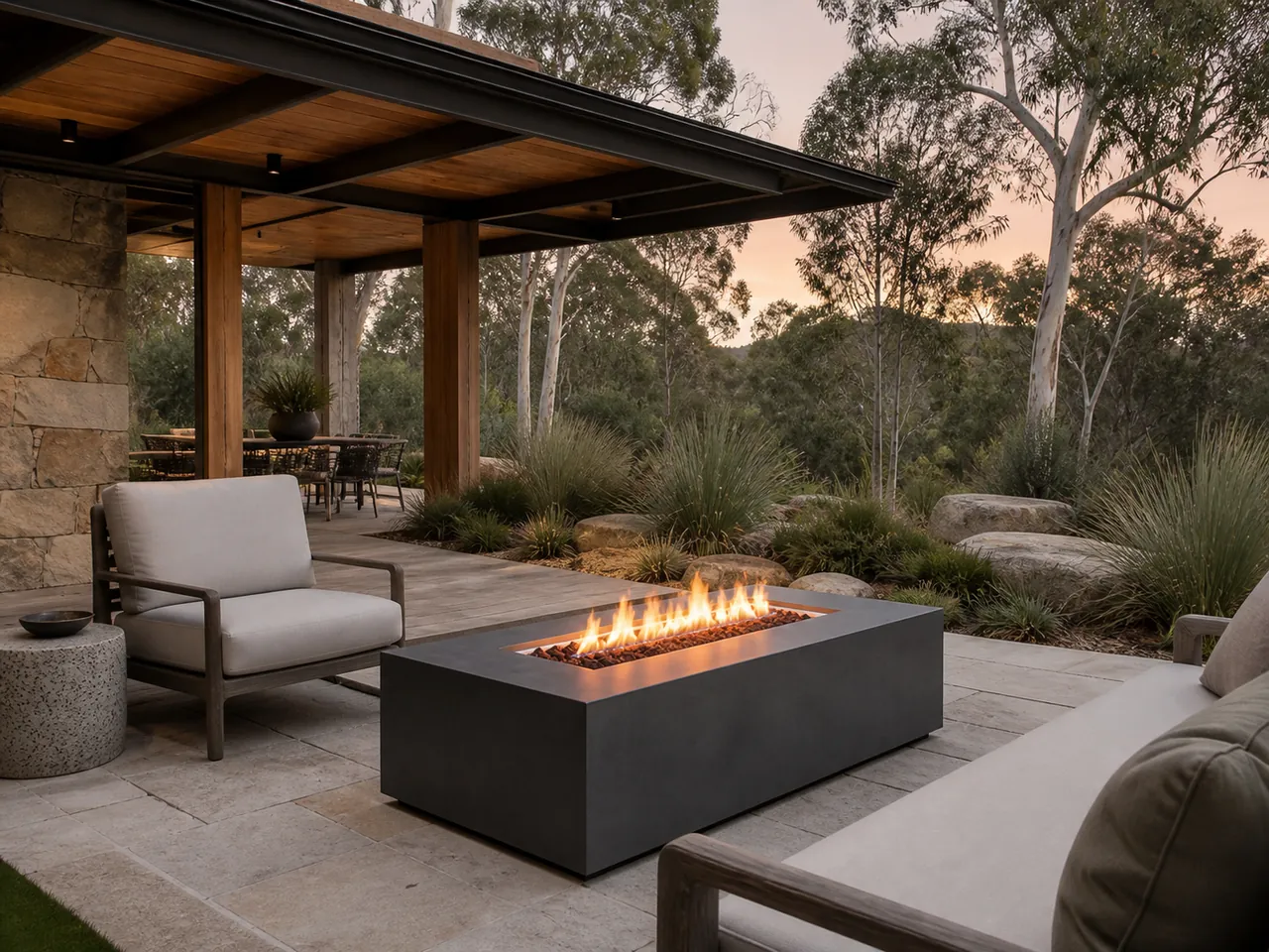 Yara Rectangular Linear Gas Fire Pit with a long flame on a stone terrace overlooking a forest landscape.