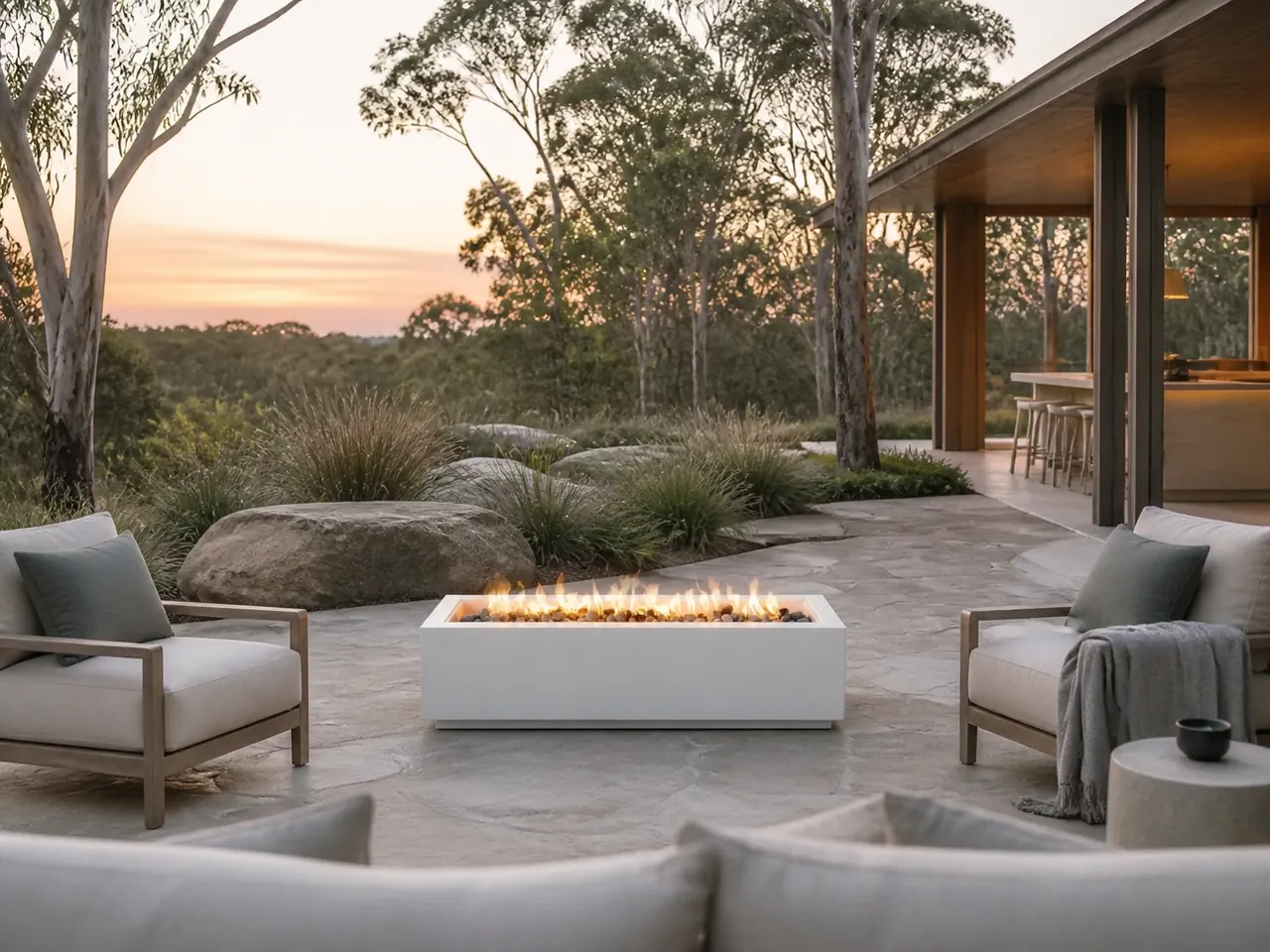 Front view of the white Nova Rectangular Linear Gas Fire Pit with a row of flames on a stone patio during a clear sunset.